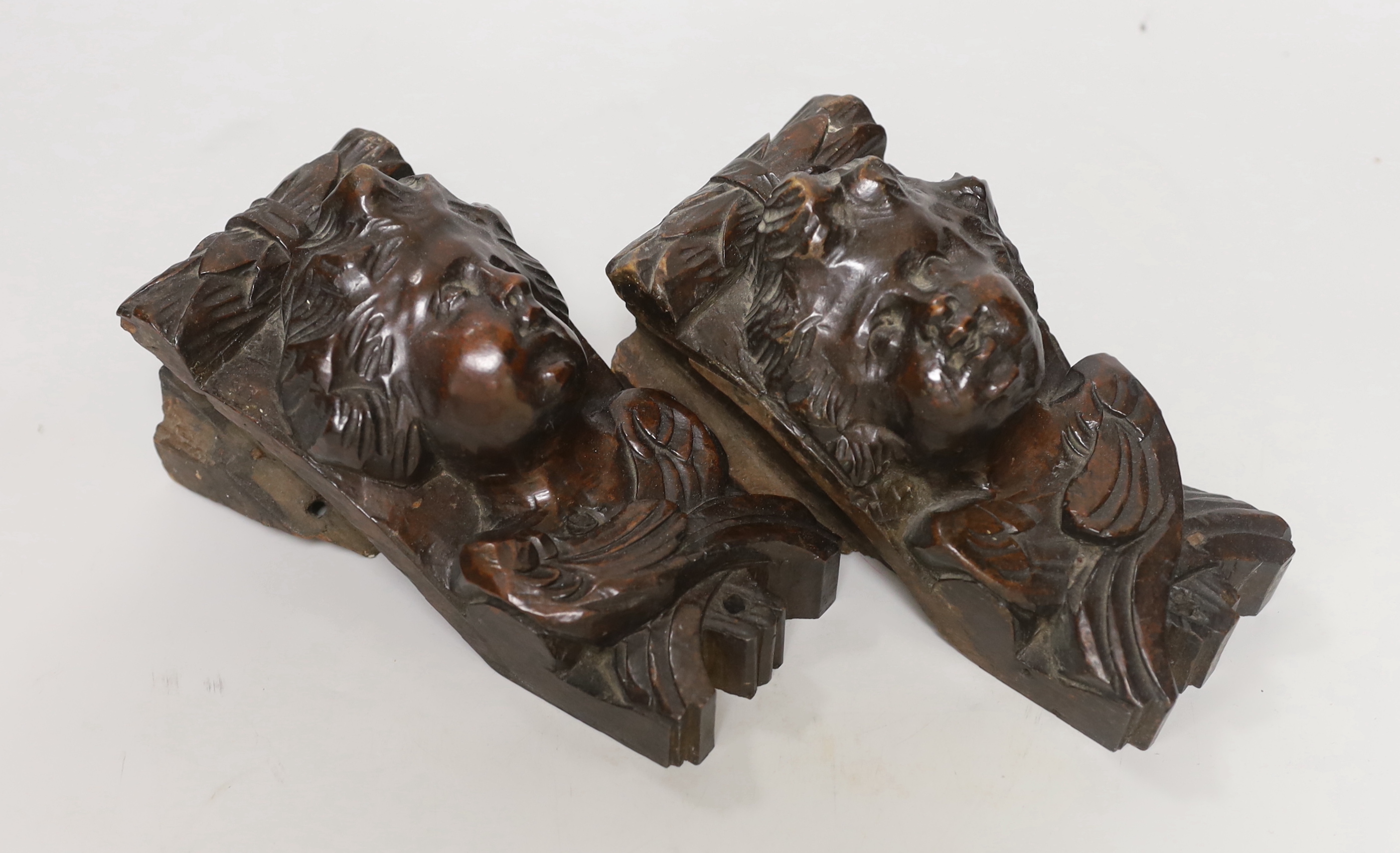 A pair of Italian carved walnut putti corbels, 18cm high